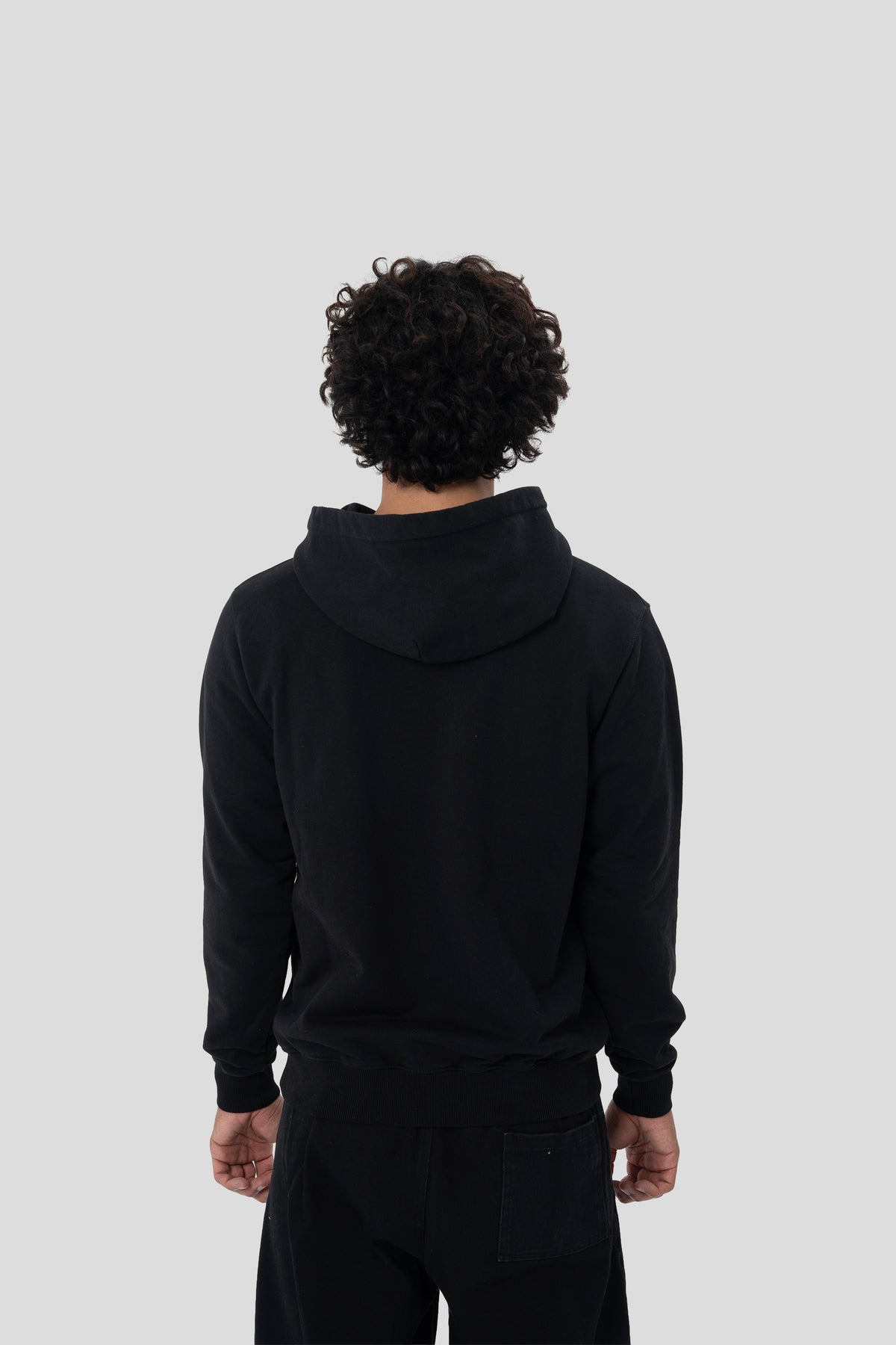 Man wearing the HUMÆ Founder Hoodie in Deep Black, shown from the back