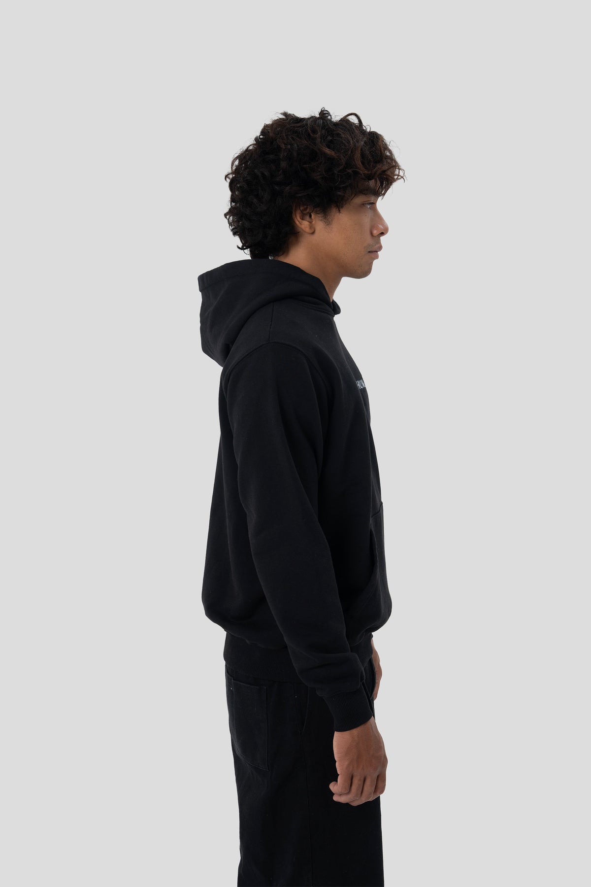 Man wearing the HUMÆ Founder Hoodie in Deep Black, shown in side profile