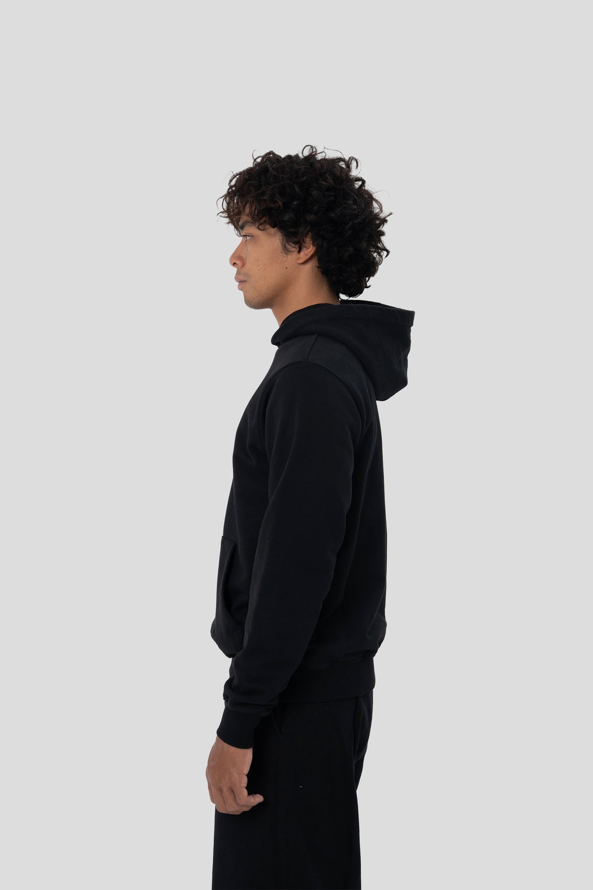 Man wearing the HUMÆ Founder Hoodie in Deep Black, shown in a full side view