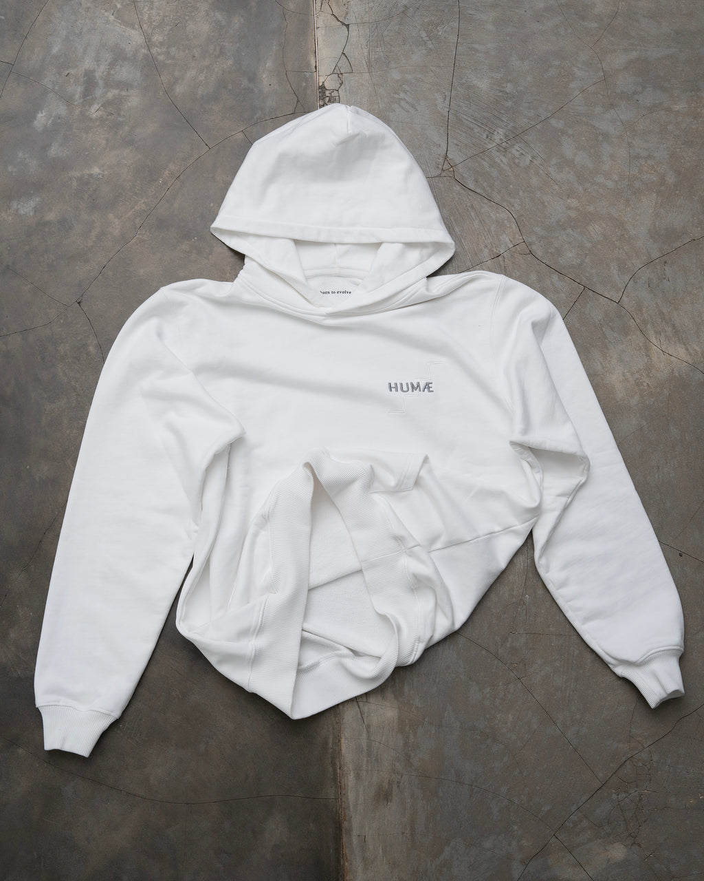 HUMÆ Founder Hoodie in Optical White laid flat, featuring the embroidered HUMÆ chest logo