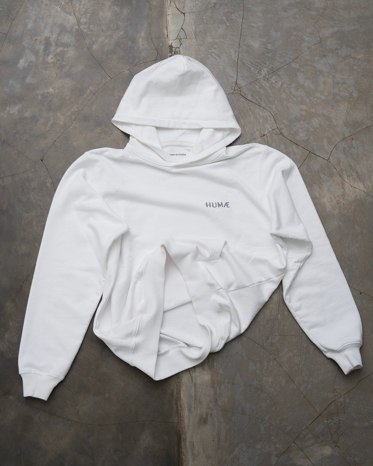 HUMÆ Founder Hoodie in Optical White laid flat, featuring the embroidered HUMÆ chest logo